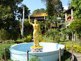 Pokhara Karma Dubgyu Chokhorling Monastery 02 Buddha Statue With Arm In The Air Welcomes You To The Garden At The Entrance Pathway